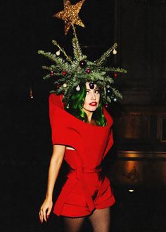 a woman in a red dress with a christmas tree on her head and stars above her head