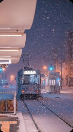 a train traveling down tracks next to a loading platform in the snow with traffic lights on