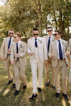 a group of men standing next to each other wearing suits and sunglasses on their heads