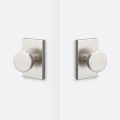 two square knobs on the side of a white wall with one button in the middle