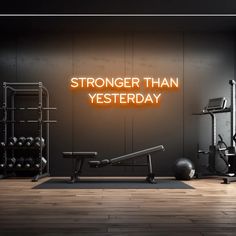 there is a neon sign that says,'strong than yesterday'in front of an exercise room