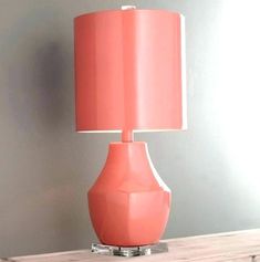 a lamp that is on top of a wooden table in front of a gray wall