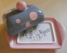 a pink and gray polka dot covered dish on a wooden table