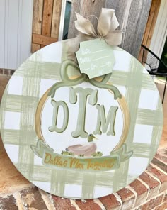 a wooden sign that says d m with a bow on it's head and the word d m written in gold