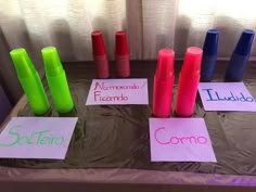 several different colored cups sitting on top of a table next to papers with words written on them