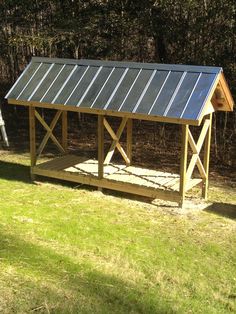 a small wooden structure with a solar panel on top in the middle of a grassy area