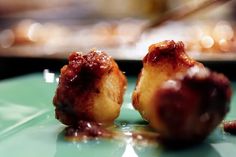 two pieces of food sitting on top of a green plate covered in jelly and sauce