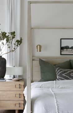 a bed with white linens and green pillows