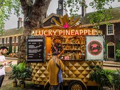 a man and woman standing in front of a food truck that is selling pineapples