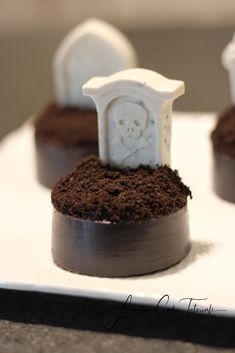 three small tombstones with dirt in them sitting on a white tray next to each other