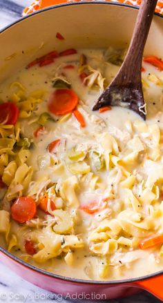 a pot full of pasta and vegetables with a wooden spoon in it, on an orange towel