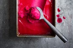 a scoop of ice cream on top of a metal tray with a spoon in it