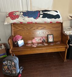 a wooden bench sitting on top of a hard wood floor next to a bag and suitcase