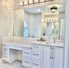 a large bathroom with white cabinets and marble counter tops is pictured in the mirror above the sink