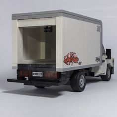 a toy truck with graffiti on the side and back door open, sitting in front of a white background