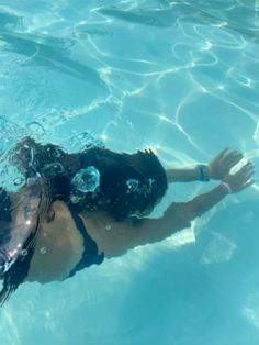 a woman swimming in the water with her hand up to her face and wearing goggles