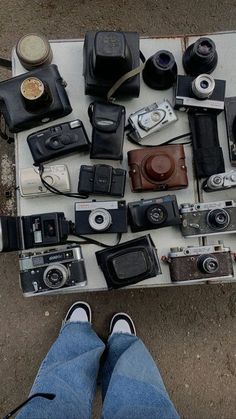 a person standing next to a table full of old cameras