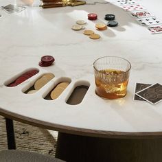 a marble table topped with a glass filled with liquid and lots of different types of playing cards