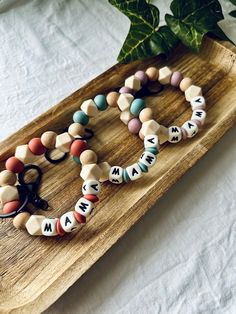 two bracelets are sitting on a wooden tray next to a potted green plant