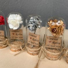 four glass jars filled with different types of flowers and twine on top of a table