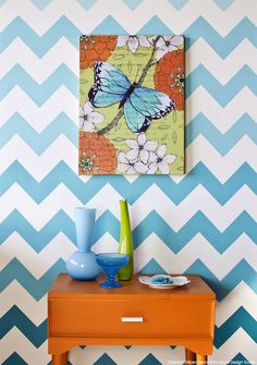 a blue and white chevron wall with a butterfly painting on it's side