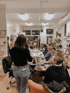 a group of people sitting around a table in a room with lots of books on it