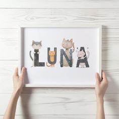 two hands holding up a framed photo with the word lunaa spelled in cats and kittens