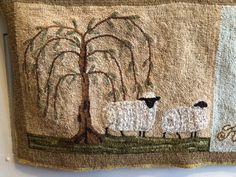 two sheep standing in front of a tree on a wall hanging from the side of a building