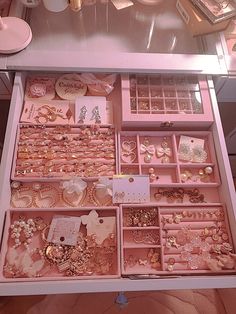 a pink jewelry box filled with lots of different types of earrings and necklaces on top of a table