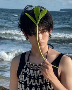 a man standing on the beach holding a plant in his hand