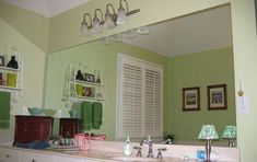 there is a bathroom with green walls and white counter tops in the mirror, along with several framed pictures on the wall