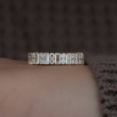 a woman's hand with a gold and diamond ring on her left arm,