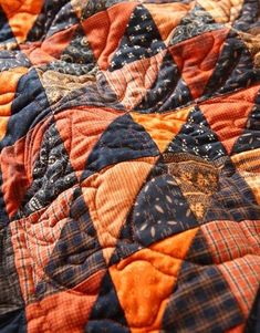 an orange and black quilt on top of a bed