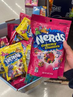 someone holding up a bag of nerds gummy clusters in front of some other snacks