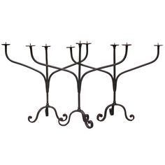 three iron candelabra with candles on each one and two hooks hanging from the top