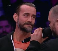 the man is getting his hair combed by another man in an orange t - shirt