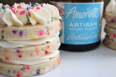 a stack of cookies with white frosting and sprinkles next to a jar of ice cream