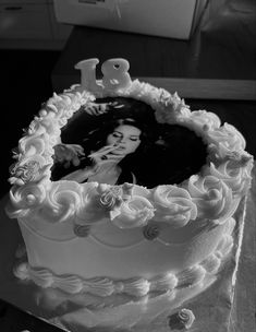 a cake with white frosting and icing on it that has an image of a woman in the middle