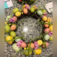 an easter wreath made out of eggs and flowers on a granite countertop next to a potted plant