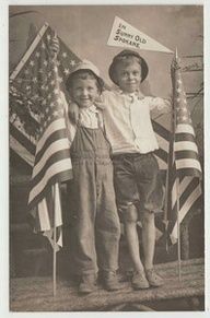 an old photo of two boys holding flags and standing next to each other in front of the american flag