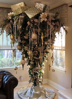 a christmas tree with ornaments hanging from it's branches in front of a window