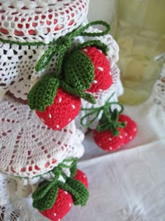 two crocheted strawberries are hanging from a white doily on a table