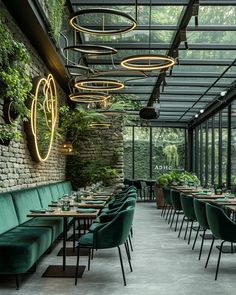 an indoor dining area with green velvet chairs and tables, surrounded by greenery on the walls