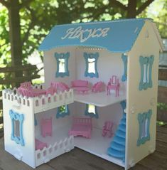 a doll house with furniture and accessories on a wooden table in front of some trees