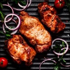 grilled meat with onions, tomatoes and herbs on a black grill grate top