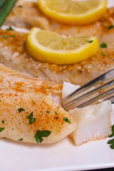 a plate with fish, lemon and asparagus garnished with parsley