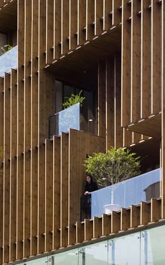 a man standing on the balcony of a building with trees growing out of it's balconies