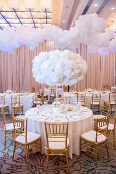 a table set up with white linens and balloons in the shape of clouds for a wedding reception