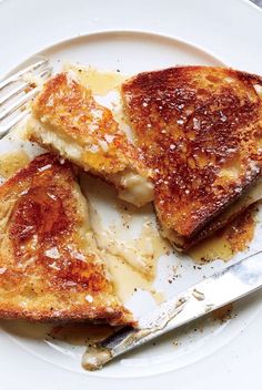 two pieces of french toast on a white plate with a fork and knife next to it