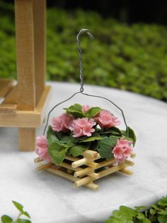 a miniature planter with pink flowers in it sitting on a white cloth covered table